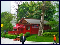 A red wooden structure in the middle of glass and steel buildings.